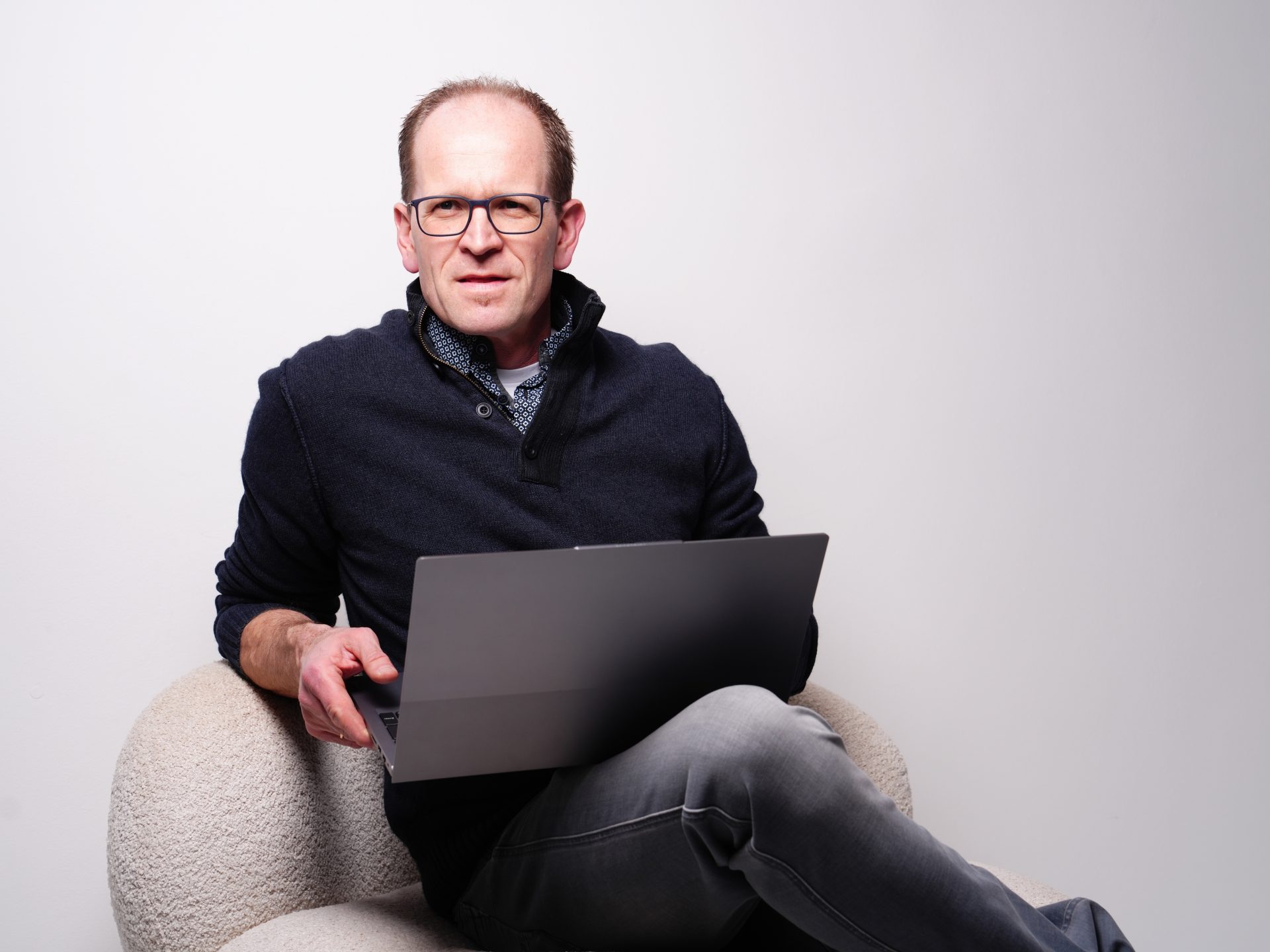 Ein Mann sitzt auf einem Sofa und arbeitet an einem Laptop.